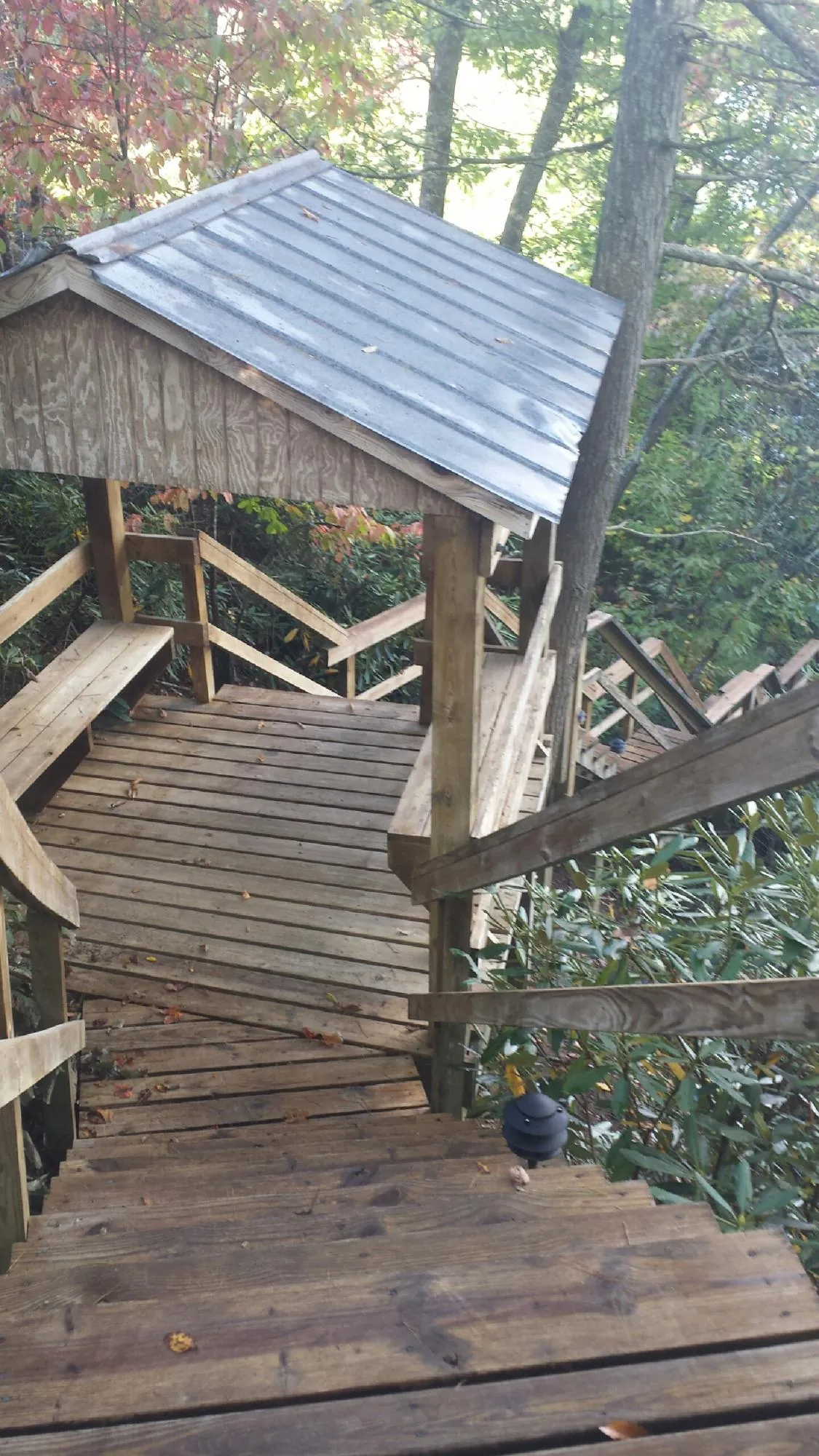 Metal roofed shelter over wooden steps on a wooded walkway — Skylight Repair & Installation work by our crew in Utica